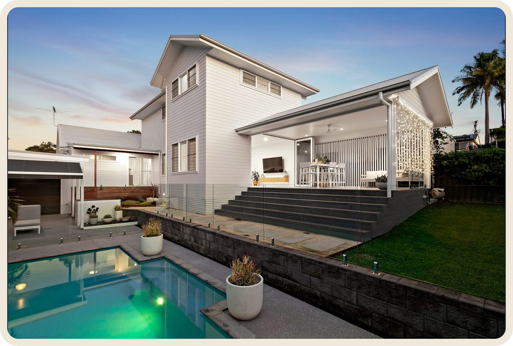White home with a generous covered outdoor living area opening onto a backyard and pool